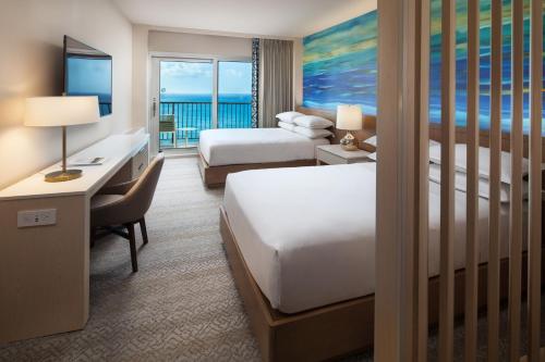 檀香山Sheraton Waikiki Beach Resort的酒店客房配有两张床、一张书桌和一张书桌
