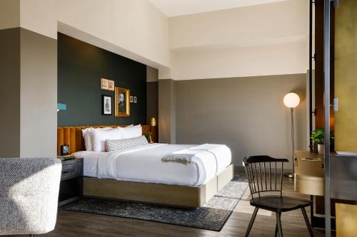 托皮卡Cyrus Hotel, Topeka, a Tribute Portfolio Hotel的配有一张床和一把椅子的酒店客房