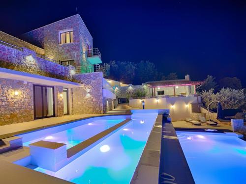 斯基亚索斯镇Sky Sea Resort & Villas的夜间在房子前面的游泳池