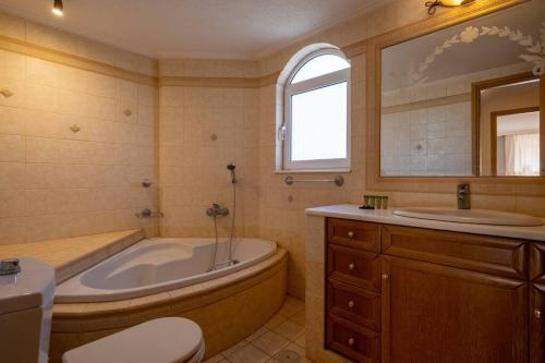 帕莱弗齐亚Phoceus Poolfront Grande Villa的带浴缸、卫生间和盥洗盆的浴室