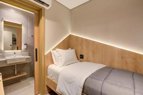 瓜鲁柳斯Fast Sleep Suites by Slaviero Hoteis - Hotel dentro do Aeroporto de Guarulhos - Terminal 2 - desembarque oeste的一间带床和水槽的小卧室
