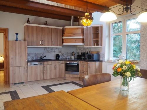 约阿希姆斯塔尔Villa Landidyll mit separatem Wellness-Bereich的厨房配有木制橱柜和花瓶桌子。