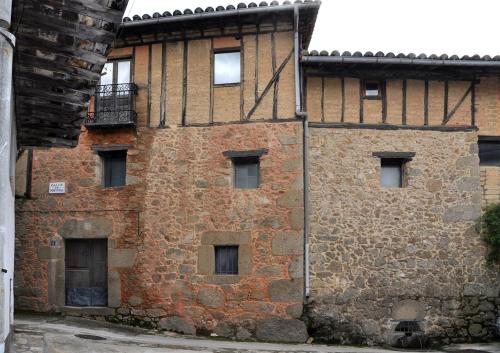 吉霍－德圣巴巴拉El jazmín de la Fuente casa rural的一座带窗户和阳台的旧砖砌建筑