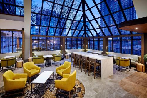 米西索加Delta Hotels by Marriott Toronto Mississauga的大堂设有黄色椅子和大型玻璃天花板