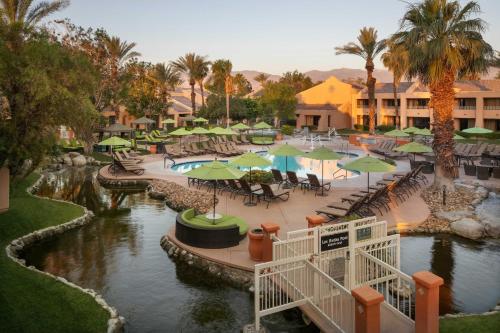 兰乔米拉日The Westin Rancho Mirage Golf Resort & Spa的一个带桌子和遮阳伞的游泳池的度假酒店