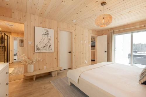 彻特西Chalet le Chardonnay - Spa , Foyers , Accès plage Lac-Jaune的卧室设有白色的床和大窗户