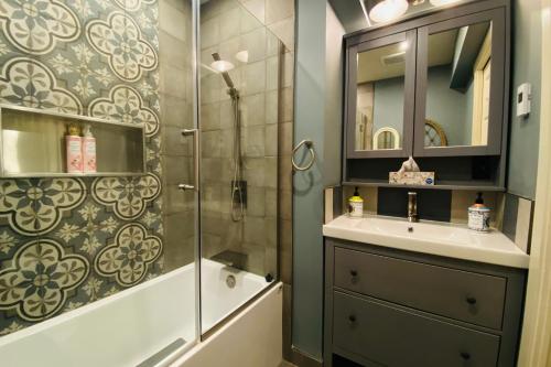 温哥华Neocolonial Nouveau Kensington的带淋浴、盥洗盆和镜子的浴室