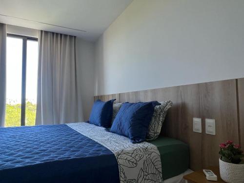 科斯塔萨乌佩Casa da Laguna - Costa do Sauipe的一间卧室配有一张带蓝色枕头的床和一扇窗户。