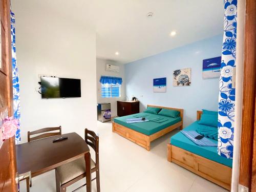 BingagBlue Summer Suites的客房设有两张床、一张桌子和一张书桌。