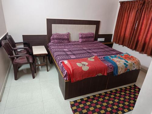 BelūrSri vishnu krupa lodging的卧室配有1张床、1张桌子和1把椅子