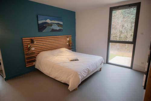 沃勒维克L'Orée des Sources的一间卧室配有一张带木制床头板的床和窗户。