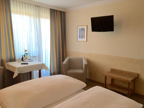 慕尼黑索纳尔霍夫酒店的酒店客房配有一张床、一把椅子和一台电视。