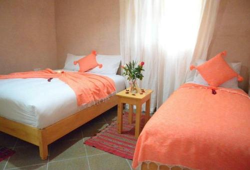 索维拉Riad Essaouira的一间卧室设有两张带橙色床单的床和窗户。