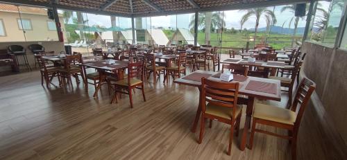 布鲁马迪纽Chalezinho Pousada的餐厅设有木桌、椅子和窗户。