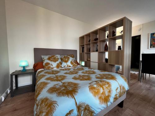 布洛涅-比扬古Spacieux studio sur jardin, beaucoup de charme的一间卧室配有一张带棕榈树大床罩的床。