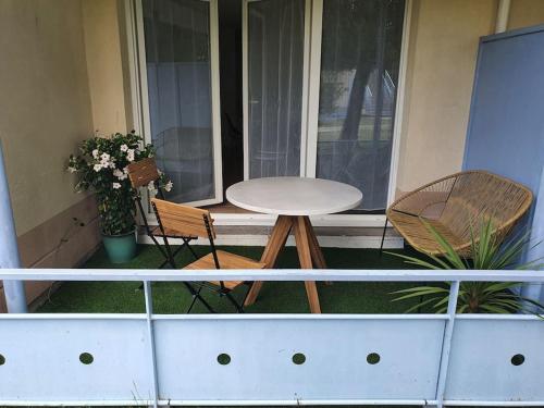 比斯卡罗斯Mignon appartement en résidence avec piscine的阳台的门廊上配有桌子和两把椅子