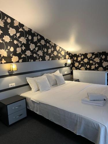巴克乌Noblesse Bacău的卧室配有一张白色大床和花卉壁纸