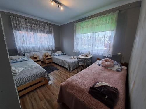 新松奇Pokoje Gościnne u Grażynki的一间卧室设有两张床、一张桌子和窗户。