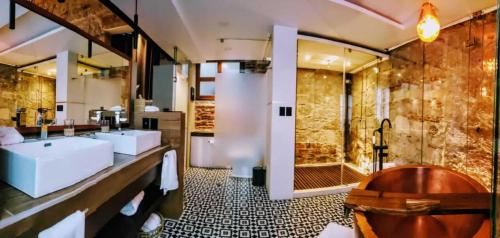 莫雷利亚Hotel Boutique Rayón 50的带浴缸、三个盥洗盆和淋浴的浴室