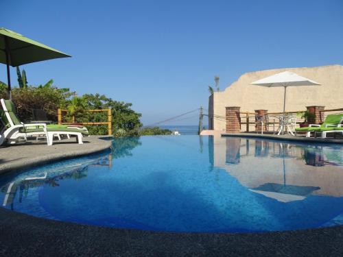 萨尤利塔Villas Vista Suites的一个带椅子和遮阳伞的游泳池