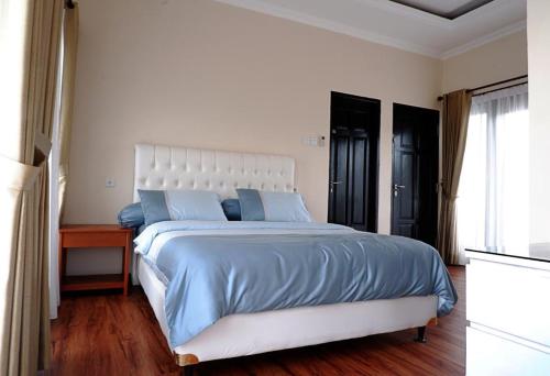 巴厘巴板Blue Villa的一间卧室配有一张带蓝色床单的大床和窗户。