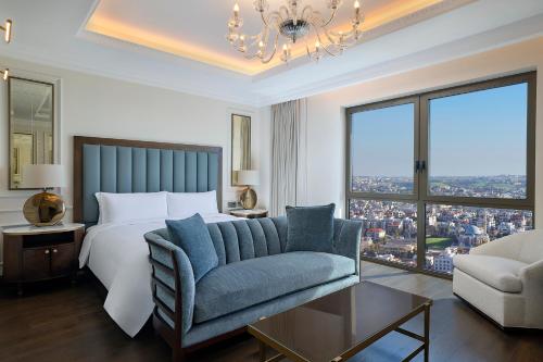 安曼The Ritz-Carlton, Amman的一间卧室配有一张床、一张沙发和一个吊灯。
