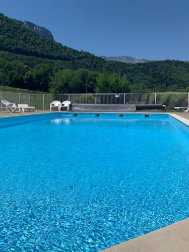 日耶Petit cocon entre lac, golf et montagne, proche d'Annecy的一个带两把椅子的大型蓝色游泳池,山脉