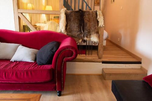 圣帕尔杜Gîte de la Grange的坐在楼梯旁的客厅里的红色沙发