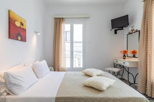 斯科派洛斯Marialena Rooms的卧室配有白色的床、书桌和窗户。