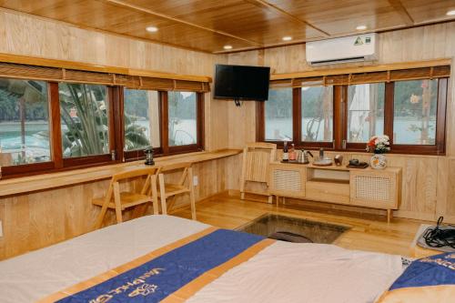 吉婆岛Lan Ha Floating Homestay的客房设有1张床、1张办公桌和1台电视。