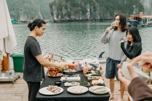 吉婆岛Lan Ha Floating Homestay的一群人站在桌子旁吃着食物