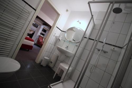 希察克尔Hotel Garni Zur Linde的带淋浴、盥洗盆和镜子的浴室