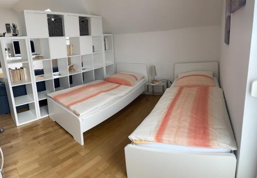 莱茵河畔韦尔特Ferienwohnung „Anhaide“的配有白色架子的客房内的两张床