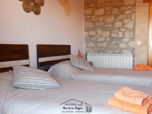 梅基嫩萨Casa Rural Mas de les Àligues的一间卧室设有两张床和石墙