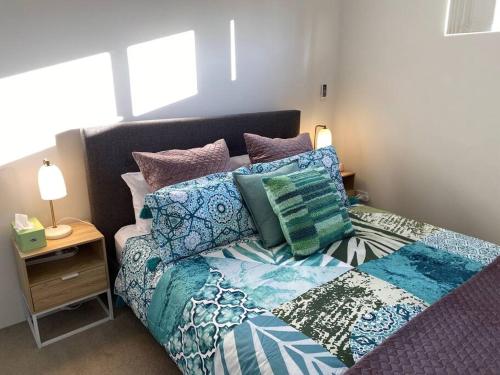 珀斯Smart Modern Close City/Airport WIFI/Park/Netflix的卧室里一张带色彩缤纷枕头的床