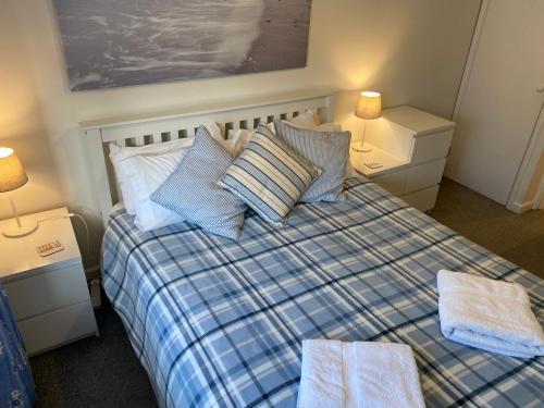 海景城Lovely 3 bed ground floor flat with garden, close to the beach, dog friendly的一间卧室配有一张带枕头的床和两盏灯。