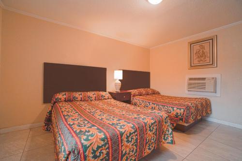 EdnaTexana Inn Edna By OYO的酒店客房配有两张床和风扇