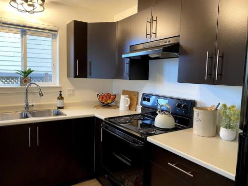 维多利亚Cozy Lakeview Suite的厨房配有黑色橱柜和炉灶烤箱。