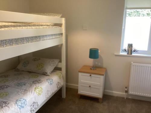 灵伍德Forest Heath Holidays - Denphyl的一间卧室配有双层床和一张带台灯的桌子