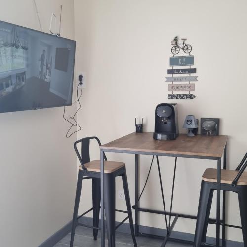 MarcorignanChambre avec piscine partagée的一张桌子、两把椅子和墙上的电视