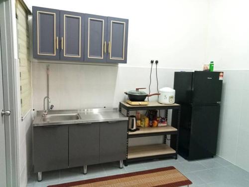 哥打丁宜DAN'S Homestay Business Suite Home的厨房配有水槽和黑冰箱。