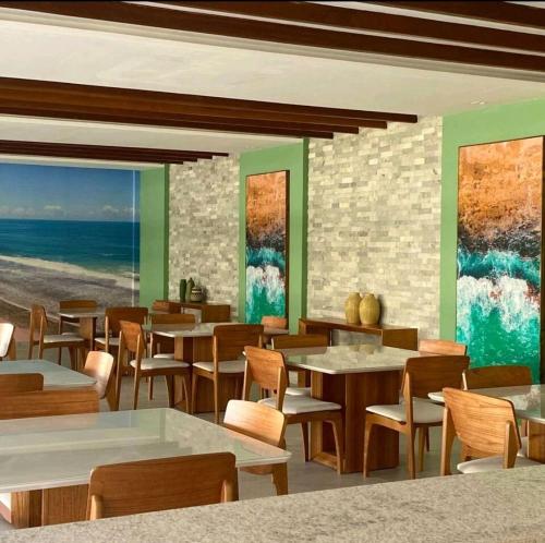 嘎林海斯港Flat luxo no Mana Beach em Muro Alto 4 pessoas的一间设有桌椅的海洋餐厅