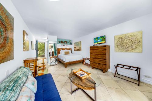 科纳DOWNTOWN PARADISE GARDEN HOTEL CONDO with Hot Tub, Pool & Beach的客厅配有蓝色的沙发和床。