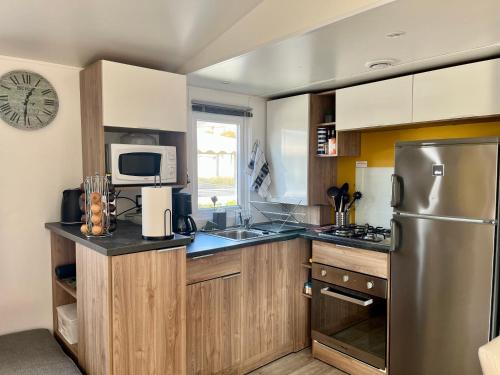 弗雷瑞斯Mobile home Zen Siblu Fréjus的厨房配有木制橱柜和不锈钢冰箱。