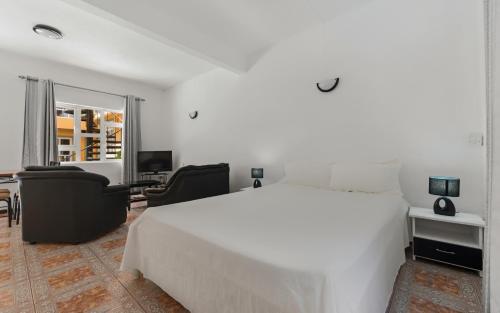 康隆尼角瓦纳一室公寓酒店的卧室配有一张白色大床和一张书桌