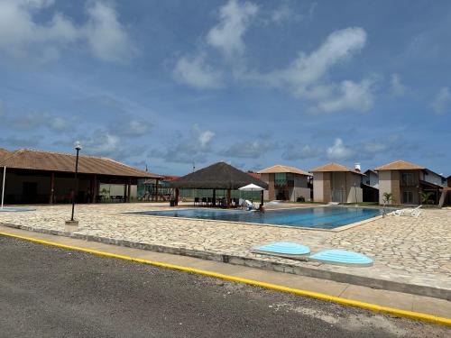 塔曼达雷Casa Praia dos Carneiros的路边带小屋的游泳池