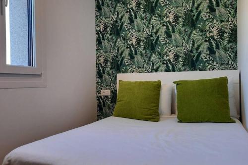 格罗韦Casa rural en San Vicente de O Grove的卧室内的一张带两个绿色枕头的床
