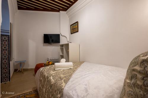 舍夫沙万Riad Bin Souaki的卧室配有一张床,墙上配有电视。