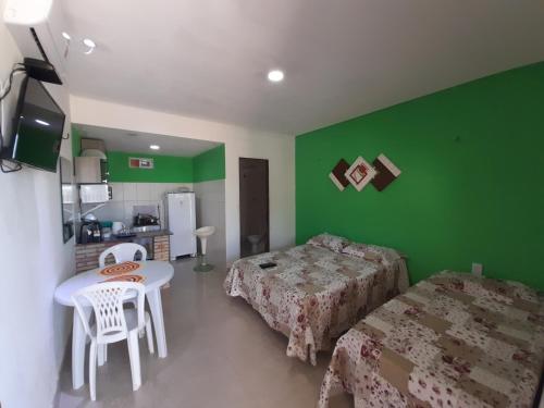 伊卡普伊Pousada Chalés do Castelo的一间设有绿色墙壁、两张床和一张桌子的房间