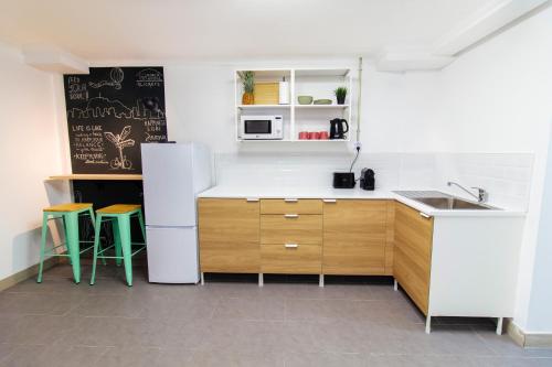 阿利坎特Koala Hostel的厨房配有白色冰箱和2张凳子